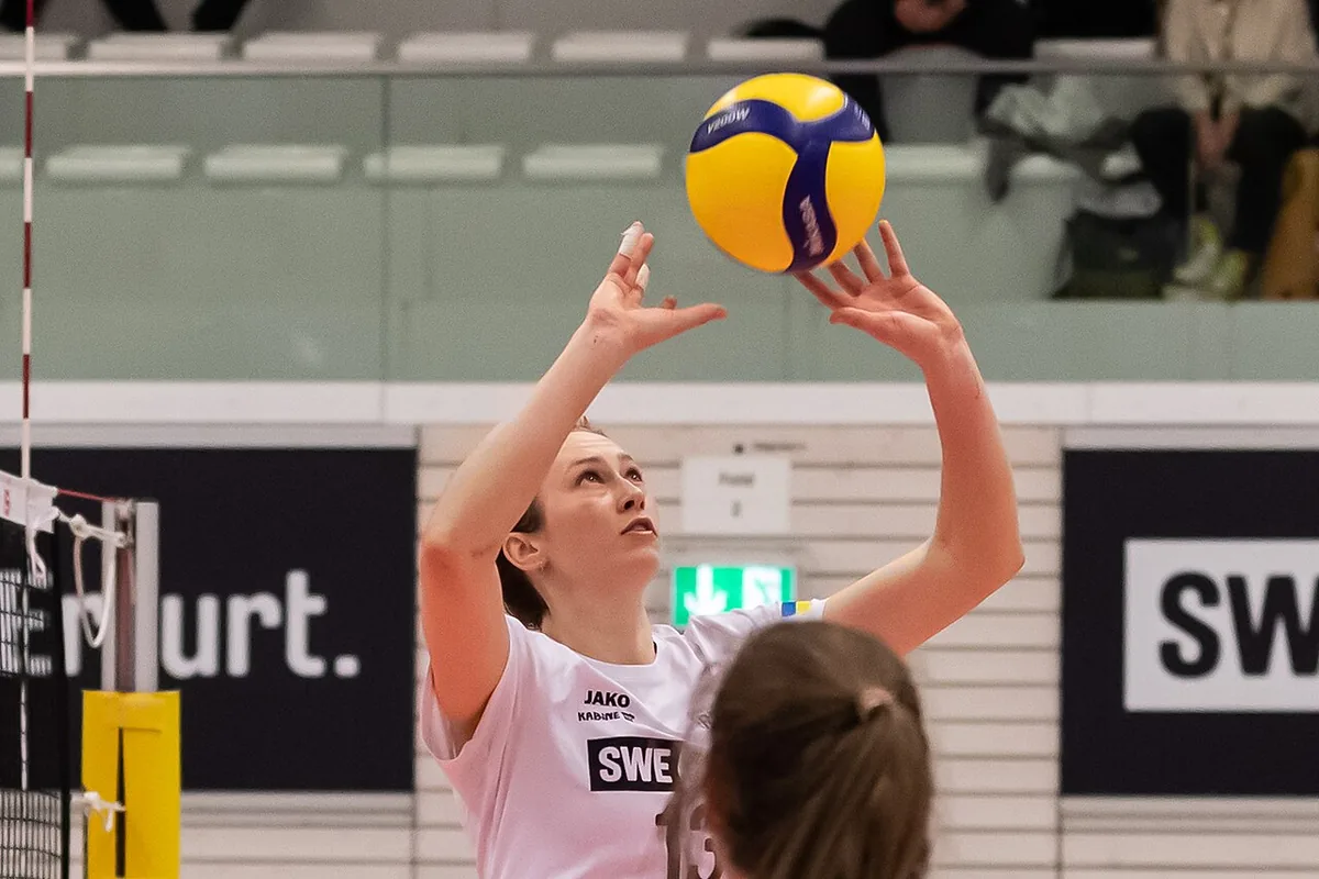 Colocadora de voleibol con los dedos abiertos y las manos por encima de la frente un instante antes de tocar el balón de dedos